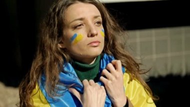 Omuzlarında Ukrayna bayrağı olan bir kadının portresi. Ukrayna 'daki savaşa ve Rus saldırısına karşı protesto.