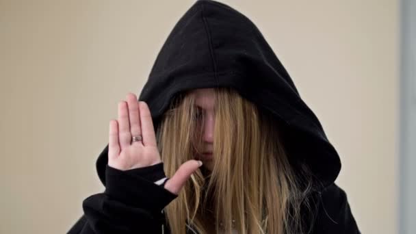 Adolescente couvrant son visage avec une capuche montre un geste indiquant une personne a besoin d'aide. — Video