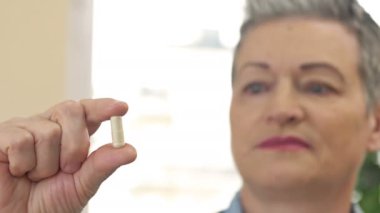 Elinde balık yağı kapsülü tutan kadın. Omega-3 içeren bir beslenme takviyesi olarak balık yağı kapsülleri ve sağlık hizmetleri için A vitamini yüksektir..