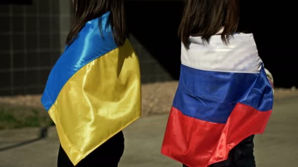 Las mujeres con banderas de Rusia y Ucrania sobre sus hombros se apartaron una de la otra. Ruptura de relaciones entre Rusia y Ucrania. Hostilidad, conflicto, guerra, agresión. — Vídeos de Stock