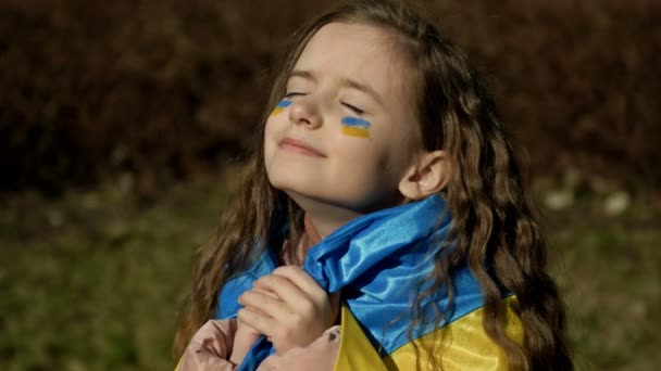 Flicka 9-10 år med Ukrainas flagga på axlarna. Krig i Ukraina. Ukrainas barn. — Stockvideo