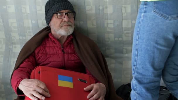 Volontaria ragazza tratta un anziano rifugiato ucraino di tè caldo, seduto in un centro per i migranti. Guerra in Ucraina. — Video Stock