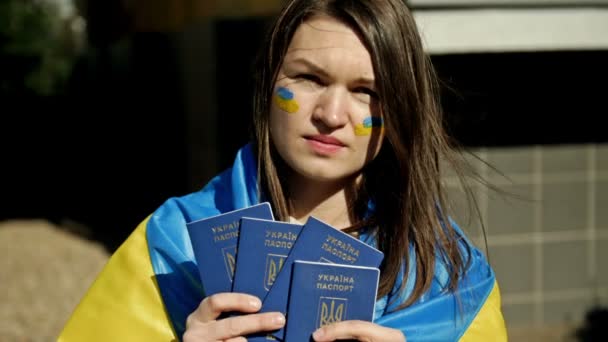 Kvinna täckt med Ukrainas flagga, med ukrainska pass i händerna. Protester mot kriget i Ukraina och rysk aggression. — Stockvideo
