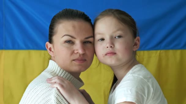 Young woman with her daughter on the background of the Flag of Ukraine. The aggressive war of Russia against Ukraine. — Stock Video