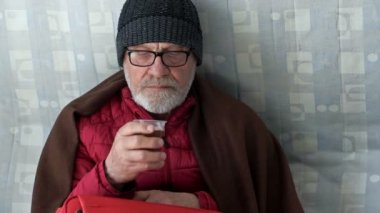 Çay içen üzgün, yaşlı bir Ukraynalı mültecinin portresi. Yerleştirme merkezinin zemininde oturuyor..