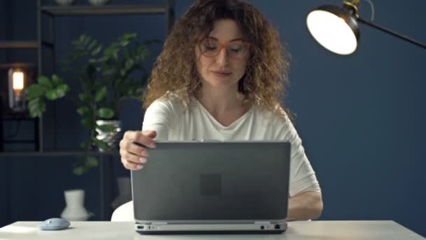 Portrett av en middelaldrende kvinne som jobber på en bærbar datamaskin. Hun er fokusert og omtenksom. Fjernarbeid. – stockvideo