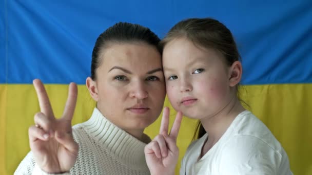 Jovem com sua filha no fundo da Bandeira da Ucrânia. Gesto do vencedor. A guerra agressiva da Rússia contra a Ucrânia. — Vídeo de Stock