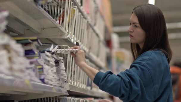 Young woman buys notebooks from the stationery department. — Vídeo de Stock