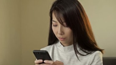 Portrait of a young Asian woman with a mobile phone in her hands. HD.