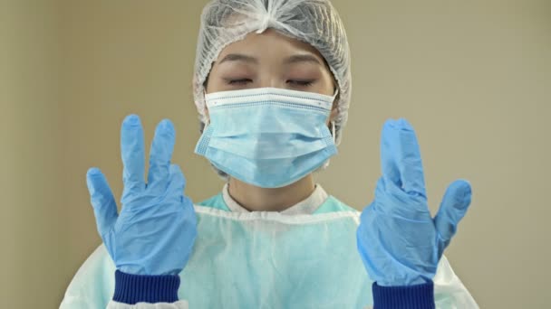 Asian female doctor or nurse in protective uniform and latex gloves prepared for procedures or operation. — Vídeo de Stock