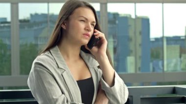 Beautiful young woman talking on the phone while standing on a city street.