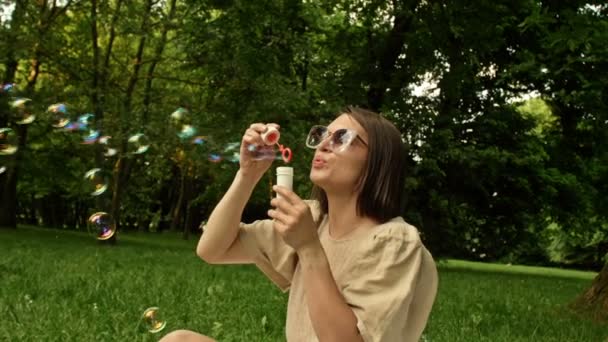 Close-up. Beautiful young woman blowing rainbow soap bubbles. A childs hand catches them. — стоковое видео