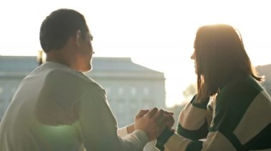 Rıhtımda romantik bir buluşma. Bir çift aşık şehrin sehpasında oturur ve neşeyle iletişim kurar, erkek kızın elini tutar..