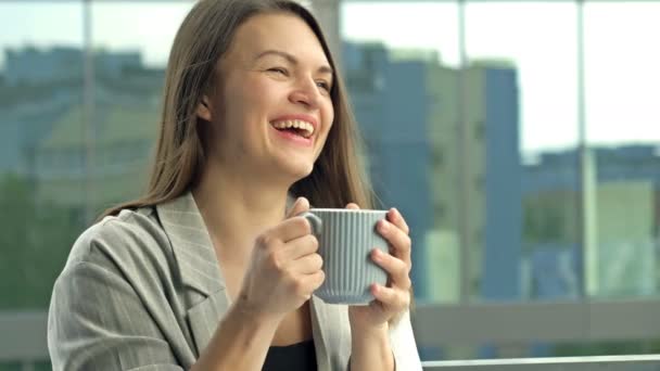 Beautiful young businesswoman drinking hot tea or coffee while standing on the office balcony. — Stockvideo