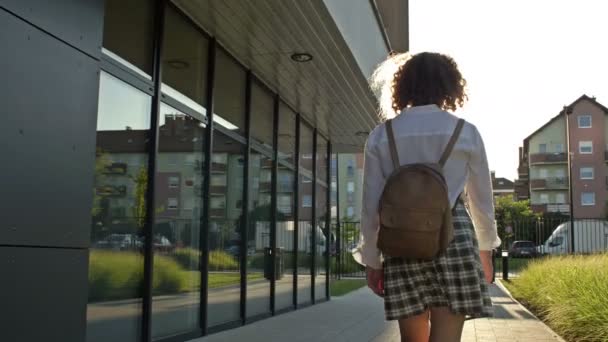 Teenage školačka, vysokoškolačka, nebo středoškolačka se vrací ze třídy. Zadní pohled. — Stock video