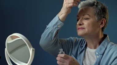 Güzel yaşlı kadın cilt bakımı için nemlendirici ve besleyici bir kozmetik ürün uyguluyor..