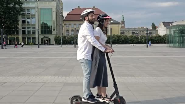 Junger Mann Fährt Mit Freundin Auf Elektroroller Auf Dem Stadtplatz — Stockvideo