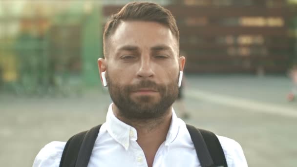 耳にワイヤレスヘッドフォンを装着した髭の中年男性の肖像画 — ストック動画