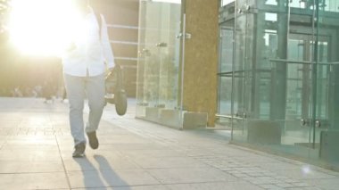 Sırt çantalı bir adam şehir caddesinde yürüyor ve katlanır bir elektrikli scooter taşıyor. Aynı zamanda, adam akıllı telefonunun ekranına da bakıyor. HD.