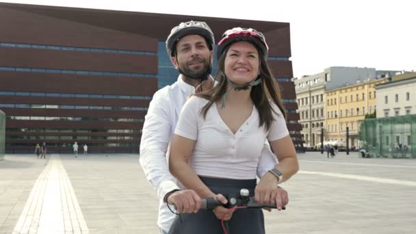 Junger Mann Fährt Mit Freundin Auf Elektroroller Über Den Stadtplatz — Stockvideo