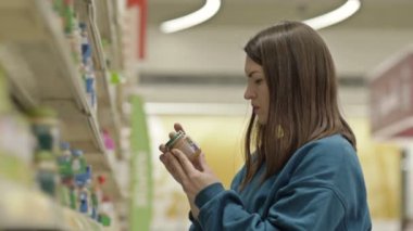 Genç müşteri, markette bebek mamasıyla rafların yanında gerekli ürünleri seçiyor. HD.