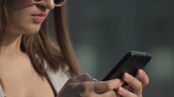 Jonge Vrouw Met Een Zonnebril Typt Een Smartphone Scherm — Stockvideo