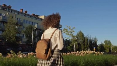 Genç liseli kız, üniversite öğrencisi ya da lise öğrencisi sınıftan dönüyor. Arkadan bak. 4K.