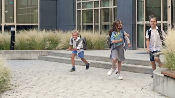 Sekelompok Siswa Sekolah Dasar Dengan Gembira Berlari Keluar Dari Gedung — Stok Video