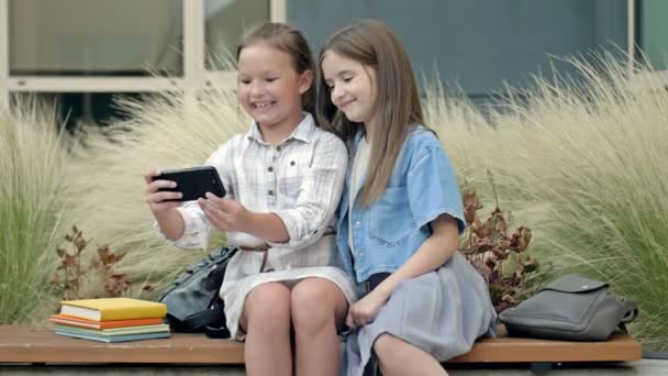 Two Girlfriends Years Old Sitting Bench School Yard Girls Looking — стоковое видео