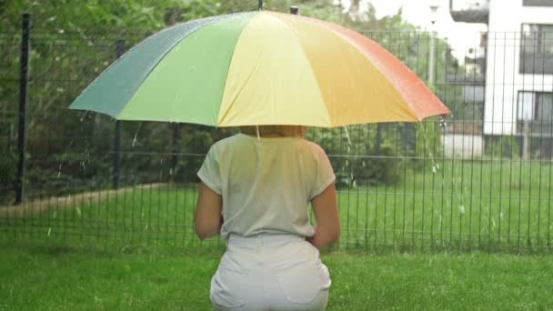 Frau Sitzt Unter Einem Hellen Regenschirm Regen Rückansicht — Stockvideo