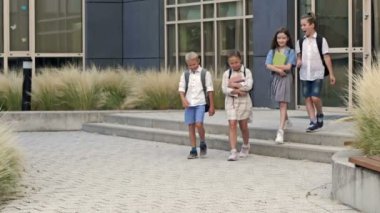 Birinci sınıf öğrencileri ders bittikten sonra neşeyle okul binasını terk ediyor. HD.