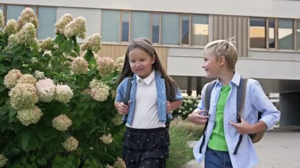 两个同学 一个男孩 一个女孩 兴高采烈地在校园里走来走去 学校的友谊4K — 图库视频影像