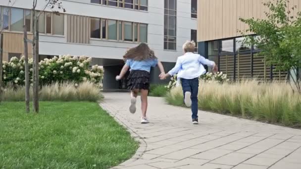 2人の子供 男の子と8 9歳の女の子は 学校の庭の周りを実行し 手を握っています 学校の友情 — ストック動画