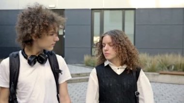 İki sevimli lise öğrencisi, bir erkek ve bir kız, üniversite bahçesinde dolaşıyorlar. Gençler canlı iletişim kuruyor. HD.