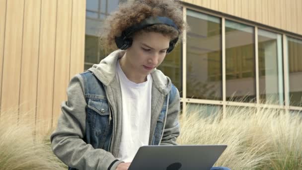 Dizüstü Bilgisayarı Kulaklığı Olan Odaklanmış Bir Genç Aynı Anda Hem — Stok video