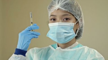 Aşı ve sağlık hizmeti konsepti. Asyalı kadın doktor, tıbbi maske takan hemşire ve aşı şırıngası tutan eldivenler. HD.