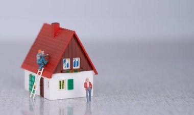 Bir çatı ustası müstakil bir evin çatısında çalışıyor. Yan görüş. Özel korumalı tulumlu bir çatı işçisi konut binasının kiremitlerini onarıyor.