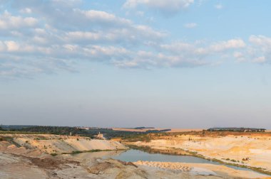 Kum ocağı. Turkuaz lagün ve yüzey mayınları açıkta kalmış renkli mineraller, çukurun dibinde ekipmanlar..