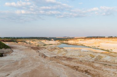 Kum ocağı. Turkuaz lagün ve yüzey mayınları açıkta kalmış renkli mineraller, çukurun dibinde ekipmanlar..