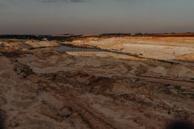 Kum ocağı. Turkuaz lagün ve yüzey mayınları açıkta kalmış renkli mineraller, çukurun dibinde ekipmanlar..