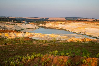 Kum ocağı. Turkuaz lagün ve yüzey mayınları açıkta kalmış renkli mineraller, çukurun dibinde ekipmanlar..