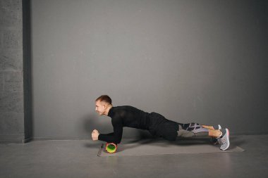 Planking. Atletik genç adam köpük silindirle spor yapıyor. Spor konsepti