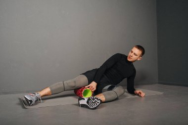Yan kalas. Atletik genç adam köpük silindirle spor yapıyor. Spor konsepti