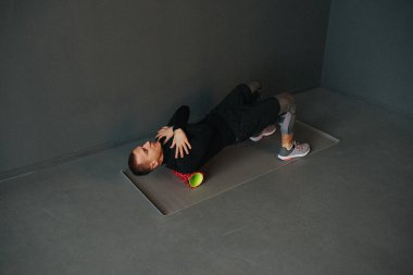 Sırtında köpükle spor yapan atletik genç bir adam. Köpük silindiri üzerinde egzersiz. Spor konsepti