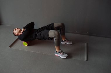 Sırtında köpükle spor yapan atletik genç bir adam. Köpük silindiri üzerinde egzersiz. Spor konsepti