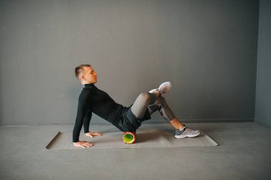 Atletik genç adam köpük silindirle spor yapıyor. Spor konsepti