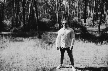 Neşeli bir adamın siyah beyaz fotoğrafı boş görünüyor. Açık havada güneş gözlüğü takıyor. Tatil 