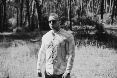 Neşeli bir adamın siyah beyaz fotoğrafı boş görünüyor. Açık havada güneş gözlüğü takıyor. Park 'ta tatil