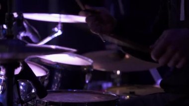 Erkekler çerçevede, büyük konser salonu sahnesinde davul çalıyorlar.