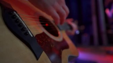 Erkek gitaristlerin yakın çekimlerinde büyük konser salonunda akustik gitar çalıyorlar.
